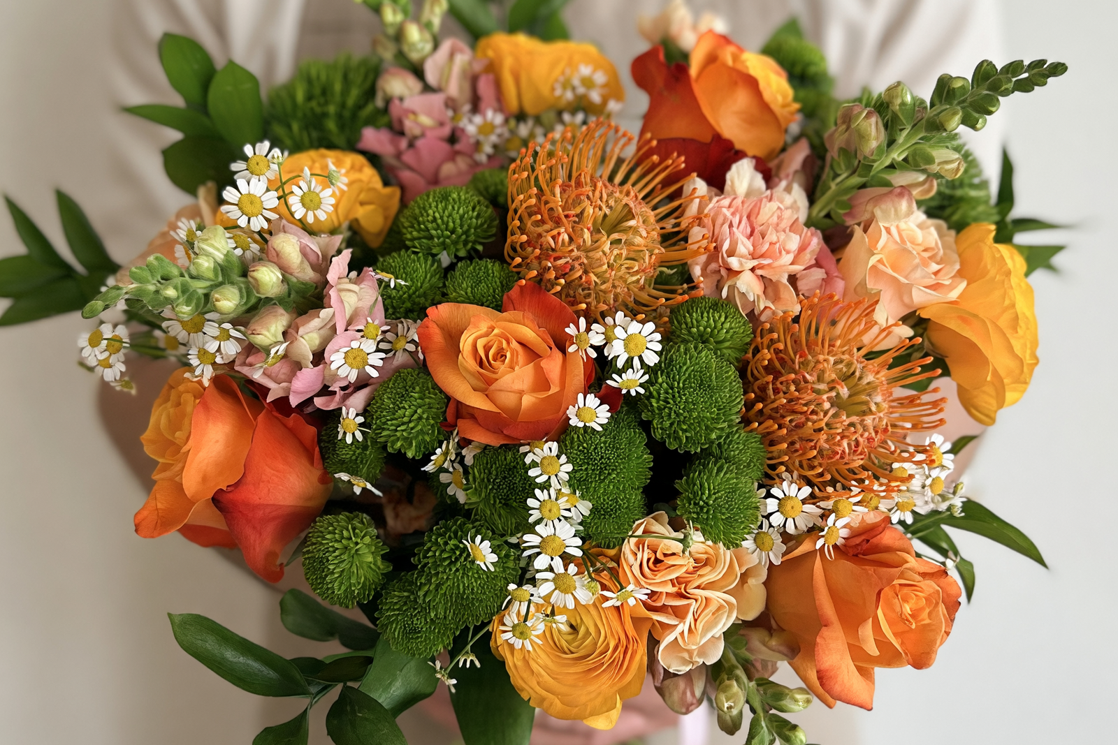 Person holding a large bouquet of flowers with a neutral background