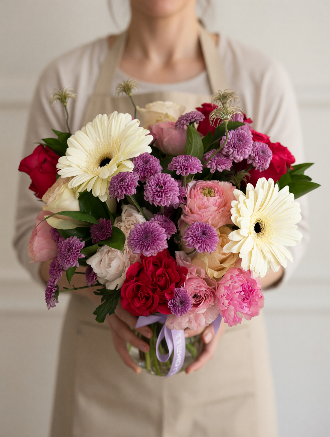 Person holding a colorful bouquet of flowers against a neutral background