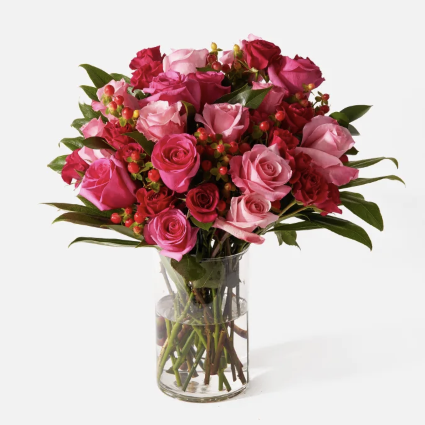 Bouquet of pink and red roses in a clear vase on a white background