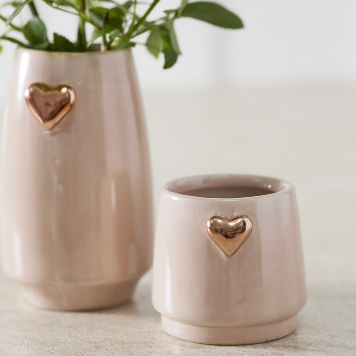 Two ceramic pots with gold heart designs on a light background