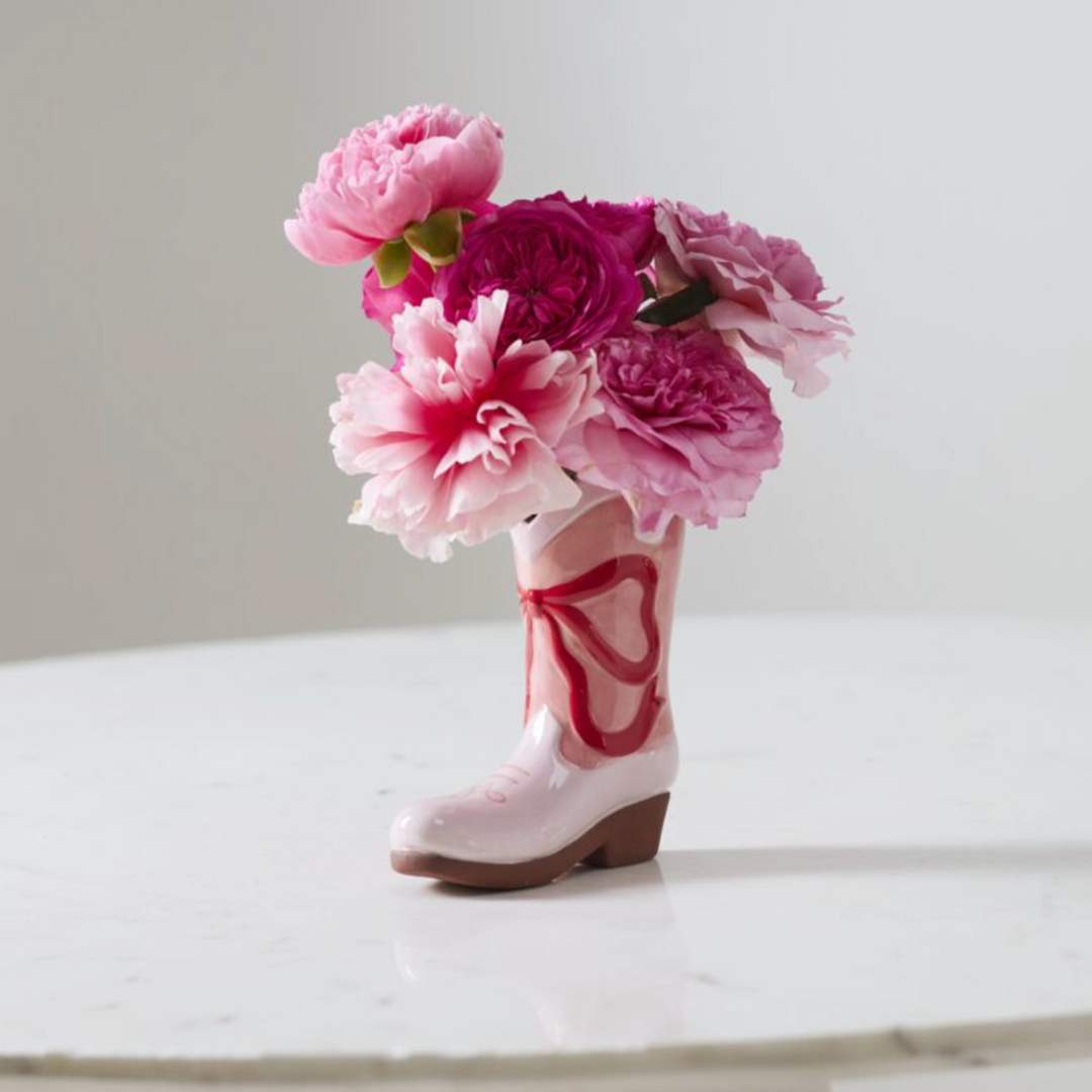 Pink cowboy boot with pink flowers on a white surface
