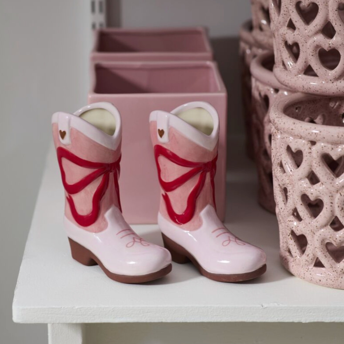Pink children's boots with butterfly design on a white surface.