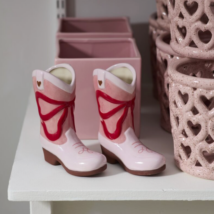 Pink children's boots with butterfly design on a white surface.
